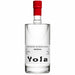 A clear glass bottle of Yola Mezcal with a white label and a bright red cap, set against a plain white background.